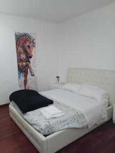 a white bed in a bedroom with a painting on the wall at APPARTAMENTO LAKE GARDA ibiscus di Francia in Desenzano del Garda