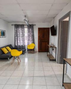 a living room with yellow chairs and a couch at Casa Little Italy in Boquerón