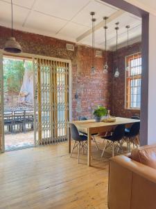 LadyBird Cottage في ديربان: غرفة طعام مع طاولة وجدار من الطوب