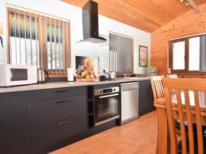 een keuken met zwarte kasten en een kookplaat oven bij 3 Bed in Clyro BN314 in Rhos-gôch