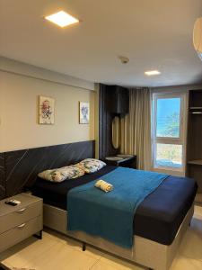 ein Schlafzimmer mit einem Bett mit blauer Bettdecke und einem Fenster in der Unterkunft Flat 201 Paradise in João Pessoa