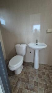 a bathroom with a toilet and a sink at Malaika Residence in Sampong