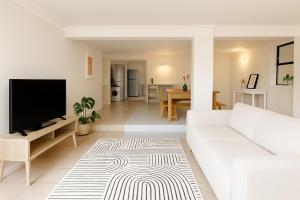 a living room with a white couch and a flat screen tv at Wildlife and Ocean Cottage in Scarborough