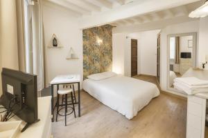 a bedroom with a bed and a desk and a tv at Le Papassaudi by La Familia in Aix-en-Provence