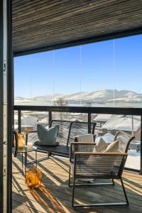 a patio with chairs and a table and a large window at Njord in Tromsø