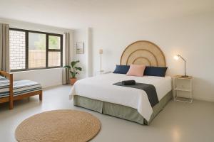 a white bedroom with a large bed with blue and pink pillows at Wildlife and Ocean Cottage in Scarborough