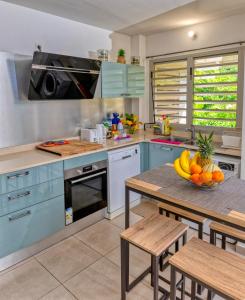 a kitchen with blue cabinets and a table with a bowl of fruit at Pom'kanelle in Le Gosier +11 photos
