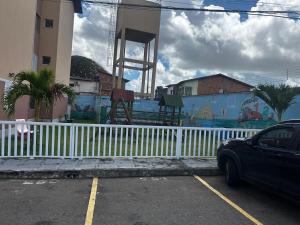 een auto geparkeerd op een parkeerplaats naast een wit hek bij Apt Eldorado perto da praia confortável para 2 a 5 pessoas in São Luís