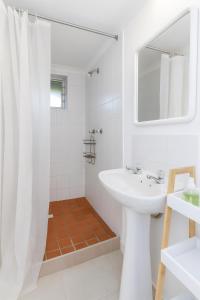 a white bathroom with a sink and a mirror at Wildlife and Ocean Cottage in Scarborough +9 photos