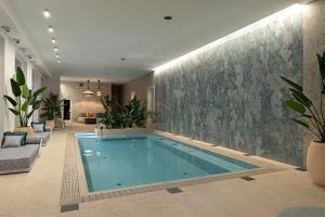 - une grande piscine dans une pièce ornée de plantes dans l'établissement Avalon Luxury Villa, à Miskolc