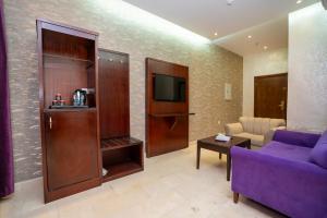 فندق جوهرة المقام الحمراء في جدة: غرفة معيشة مع أريكة أرجوانية وتلفزيون
