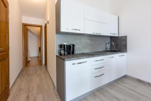 eine Küche mit weißen Schränken und einer Arbeitsplatte in der Unterkunft Apartments Sunshine E in Crikvenica + 136 Fotos