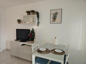 ein Esszimmer mit einem weißen Tisch und einem TV in der Unterkunft Aguila Relax Apartment in Benalmádena