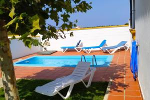 a pool with lounge chairs next to a house at Chalet Chaparrillo Conil Rentals in Conil de la Frontera +4 photos
