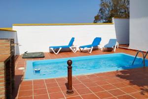 a swimming pool with two chairs and a swimming poolvisor at Chalet Chaparrillo Conil Rentals in Conil de la Frontera