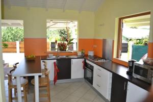 a kitchen with black countertops and orange and green walls at Maison confortable avec piscine à Goyave in Goyave