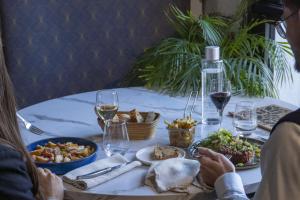 two people sitting at a table with food and wine at Hotel Restaurant l'Eskemm St Brieuc-Trégueux in Tregueux
