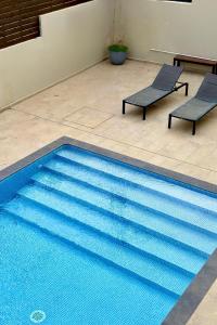 een blauw zwembad met 2 stoelen en een tafel bij Interni Villa by A&D Properties in Porto Rafti