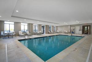 a pool in a hotel lobby with tables and chairs at Staybridge Suites Sterling Heights - Detroit by IHG in Sterling Heights