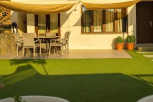 un patio con tavolo, sedie e prato verde di ARSENIa COTTAGE a Kyperounda