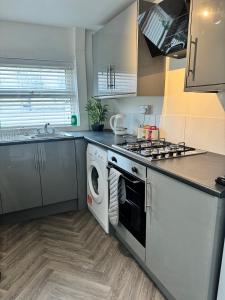a kitchen with a stove and a washing machine at Holgate Cottage in Great Harwood