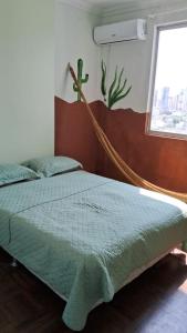 a bedroom with a bed with a green comforter and a window at Spacious & Artistic Apartment in Belém in Belém