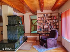 a living room with a chair and a stack of books at Erdőalja-Padlástér in Jásd