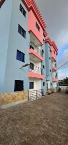 un edificio alto con balconi rosa e un parcheggio di Résidence Didi a Kribi