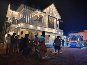 a group of people standing outside of a building at night at Rockland Holidays Ramakkalmettu in Idukki