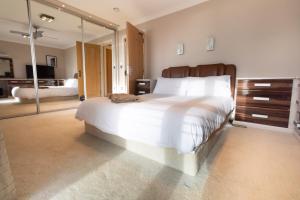 a bedroom with a large white bed and a mirror at Stunning Swansea Marina beach house with sea views in Swansea