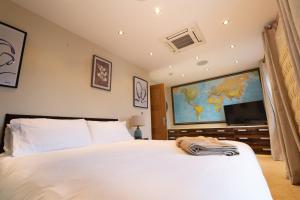 a bedroom with a white bed and a large tv at Stunning Swansea Marina beach house with sea views in Swansea