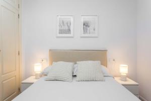 Un dormitorio con una gran cama blanca con dos lámparas. en Cozy 1BD Apartment in Alonso Martínez, en Madrid