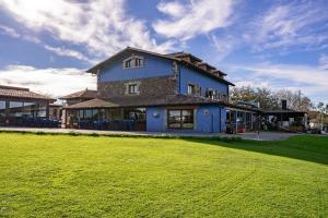 a large blue house with a green field in front of it at Casona Asturiana Los Gamonales in Logrezana