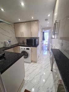 a kitchen with a washing machine and a washer at 2 bedroom Flat Heathrow in Feltham