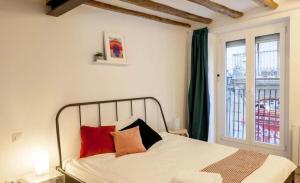 une chambre avec un lit avec des oreillers rouges et une fenêtre dans l'établissement Ramblas Apartment Central BCN, à Barcelone