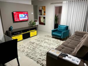 a living room with a couch and a tv at Apto no centro da cidade mais alemã do Brasil in Pomerode