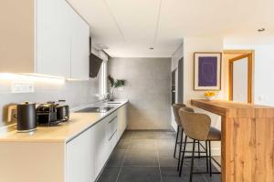 a kitchen with white cabinets and a counter with stools at Modern Stay in Plaza Castilla in Madrid +16 photos