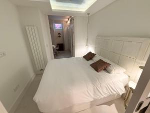 a white bedroom with a white bed with two pillows at Stylish Haven in Chic Salamanca in Madrid