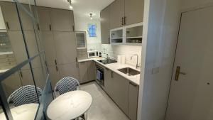 a kitchen with white cabinets and a sink and chairs at Stylish Haven in Chic Salamanca in Madrid