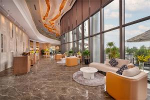 a lobby with couches and tables and windows at Nesta Celia Danang Hotel in Danang