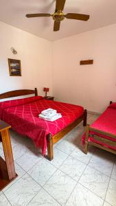 Apart hotel Bonato في La Porteña: غرفة نوم بسريرين مع شراشف حمراء ومروحة
