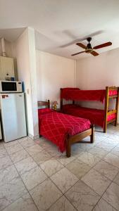 Apart hotel Bonato في La Porteña: غرفة نوم بسرير احمر وثلاجة