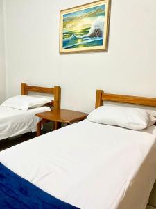 duas camas em um quarto com uma foto na parede em Apart Cavalari Kitnets em Marília