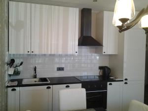 a kitchen with white cabinets and a black stove at Luxury Apartment in Druskininkai