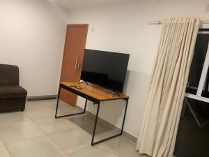 een kamer met een bureau met een televisie en een gordijn bij Vila das Orquídeas in Formosa
