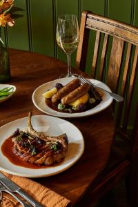 a table with two plates of food and a glass of wine at The George and Dragon - A Heartwood Inn in Marlow