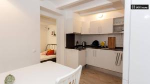 une cuisine avec des armoires blanches et un lit dans une chambre dans l'établissement Ramblas Apartment Central BCN, à Barcelone