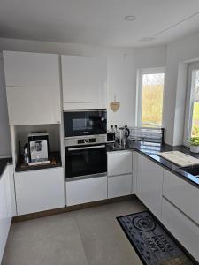 una cucina con mobili bianchi ed elettrodomestici neri di Sebastian's Chalet Royal a Ötigheim