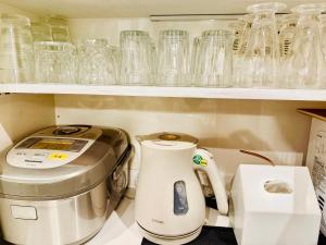 a kitchen with a coffee maker and glasses on a shelf at DP Oyamamachi Tokyo in Machida