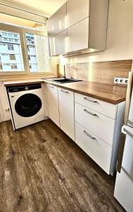 eine Küche mit weißen Schränken, einem Herd und einem Geschirrspüler in der Unterkunft Le petit savoyard in Albertville